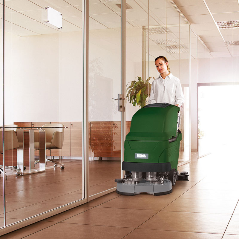 Woman walks behind a floor scrubber