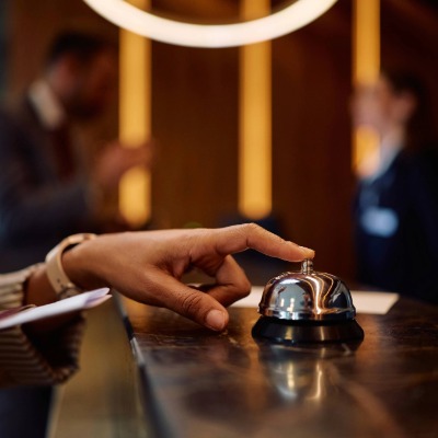Hand drukt bel in op hotelbalie