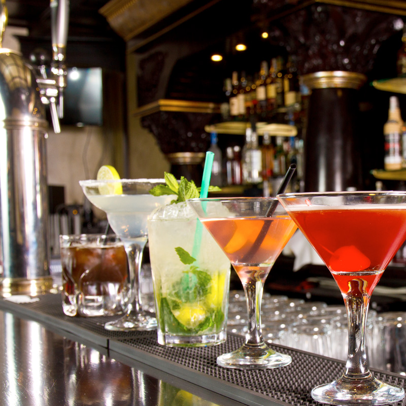 Various cocktails stand side by side on a bar